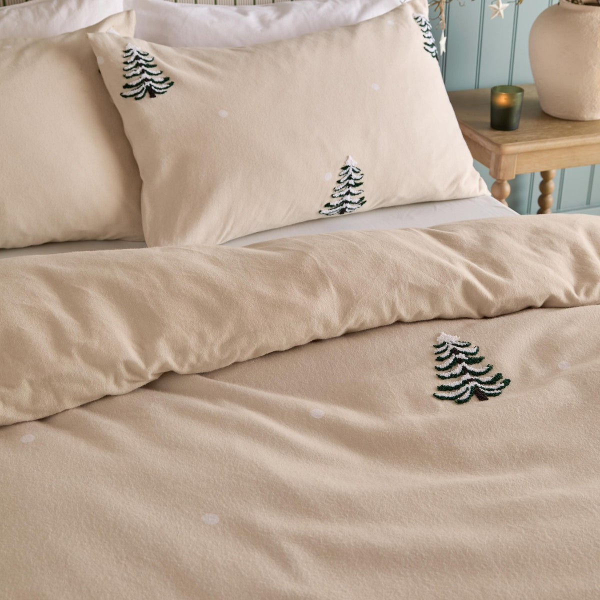 Pine Tree Cotton Woodland Duvet Cover Set in natural, shown on a bed with matching pillowcases featuring tufted pine tree motifs and scattered snow dots, in a bedroom setting.