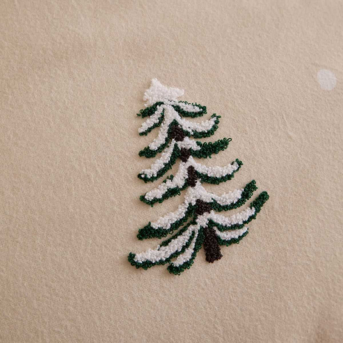 Close-up of the Pine Tree Cotton Woodland Duvet Cover Set in natural, showing a tufted green and white fir tree with brown trunk detail on brushed cotton fabric.