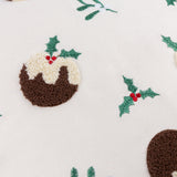Puddings Velvet Cotton Cushion in Multicolour, close-up of cream velvet fabric with a tufted brown and cream Christmas pudding motif and embroidered holly sprigs with red berries.