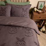 Chocolate brown duvet cover set with tufted Christmas pudding and holly motif, shown on a bed with matching pillowcases and a green cushion in a bedroom setting.