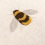 Close-up of the Rambbee Velvet Linen Cushion in Natural, showing a tufted bee in brown and gold loops with grey stitched wings on oatmeal linen.