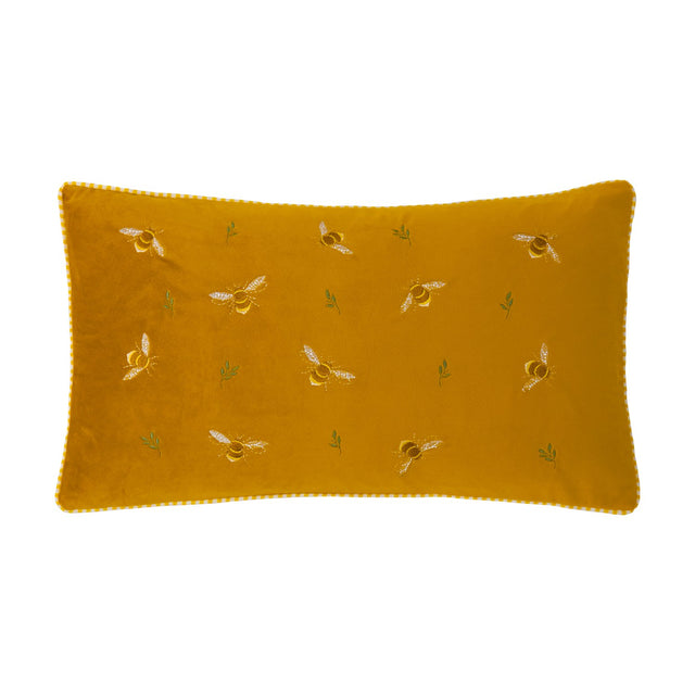 Rectangular honey gold velvet cushion with embroidered bees in cream and tan, small green leaf sprigs, and gingham-trimmed edging, shown on a plain white background.