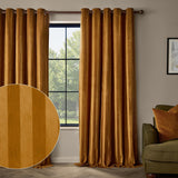 Regency Stripe Velvet Fully Lined Eyelet Curtains in antique gold, shown floor-to-ceiling either side of a window in a living room with a green sofa and striped cushion.