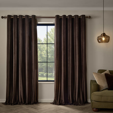 Regency Stripe Velvet Fully Lined Eyelet Curtains in chocolate brown, framing a window in a living room with a green sofa and glass pendant light.