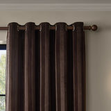 Regency Stripe Velvet Fully Lined Eyelet Curtains in chocolate brown, showing vertical pile stripes and metal eyelet heading on a wooden pole, hung by a window.