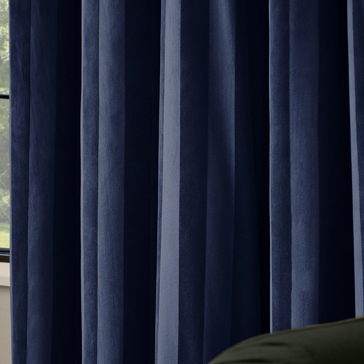 Close-up of Regency Stripe velvet eyelet curtains in Midnight navy, showing soft-pile fabric with subtle vertical stripes and deep tonal folds, hung by a window.
