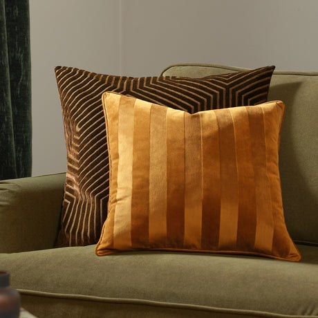 Regency Stripe Jacquard Velvet Cushion in antique gold with tonal vertical stripes and piped edging, shown on an olive green sofa beside a brown patterned cushion.