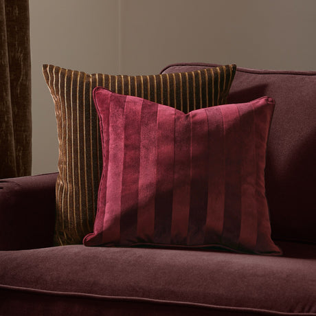 Regency Stripe Jacquard Velvet Cushion in burgundy with tonal vertical stripes, shown on a matching velvet sofa alongside a striped brown cushion.