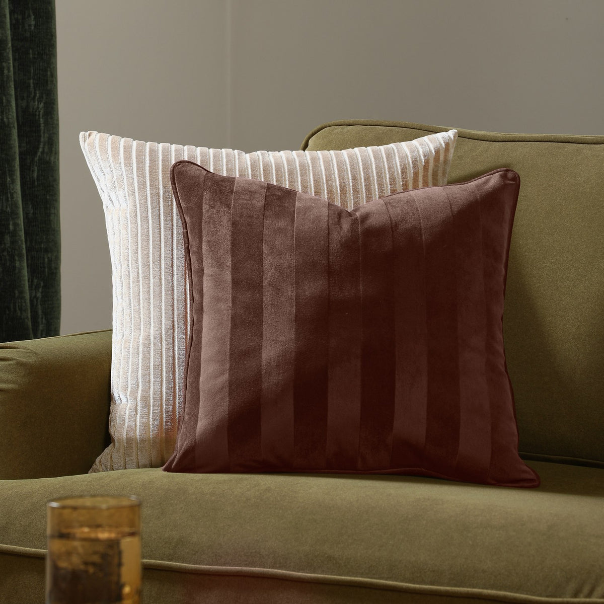 Regency Stripe Jacquard Velvet Cushion in chocolate brown with tonal striped pile, shown on an olive green sofa beside a cream ribbed cushion.
