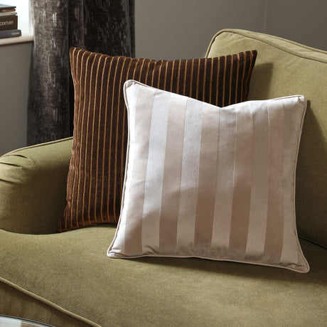 Regency Stripe Jacquard Velvet Cushion in grey with piped edge, styled on an olive-green armchair alongside a brown striped cushion in a living room setting.