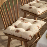 Rhighco Linen Cotton Seat Pad in natural cream, printed with highland cow and floral motifs, tufted and tied onto a wooden spindle-back dining chair.