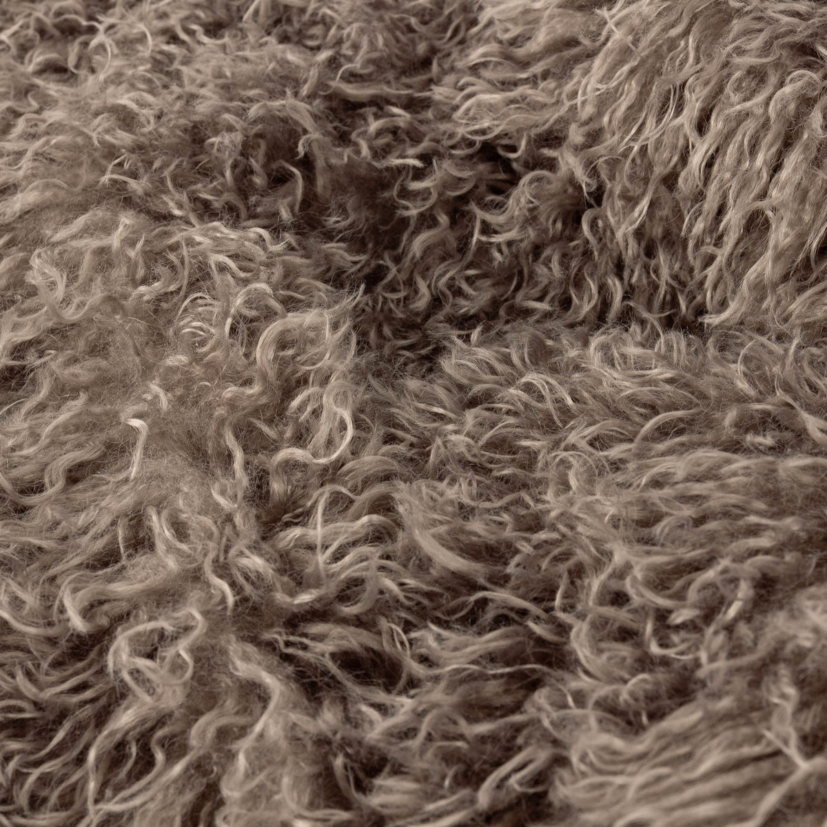 Close-up of the Rowan Faux Fur Plain Velvet Cushion in mocha brown, showing its long, curly shaggy pile with a Mongolian-style texture.