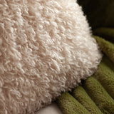 Close-up of the Rowan Faux Fur Polyester Velvet Cushion in natural cream, showing its shaggy, curly-pile texture beside a green ribbed cushion.