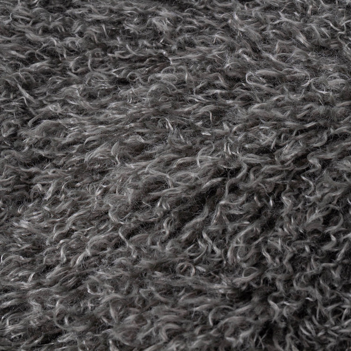Close-up of the Rowan Faux Fur Throw in grey, showing deep curly Mongolian-style fur with mottled charcoal tones and silvery tips.