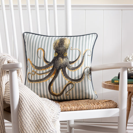 Salcombe Octopus velvet cushion with a hand-painted charcoal octopus and amber suckers on grey-blue striped fabric, shown on a white rocking chair.