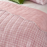 Scallop Plain Cotton Blend Bedspread on a bed, showing pink and white gingham check reverse with a scalloped white-trimmed pink quilted top edge.