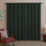 Bottle green eyelet curtains in soft chenille fabric hang full-length with dark grommets on a black rod, shown in a living room with pink walls.