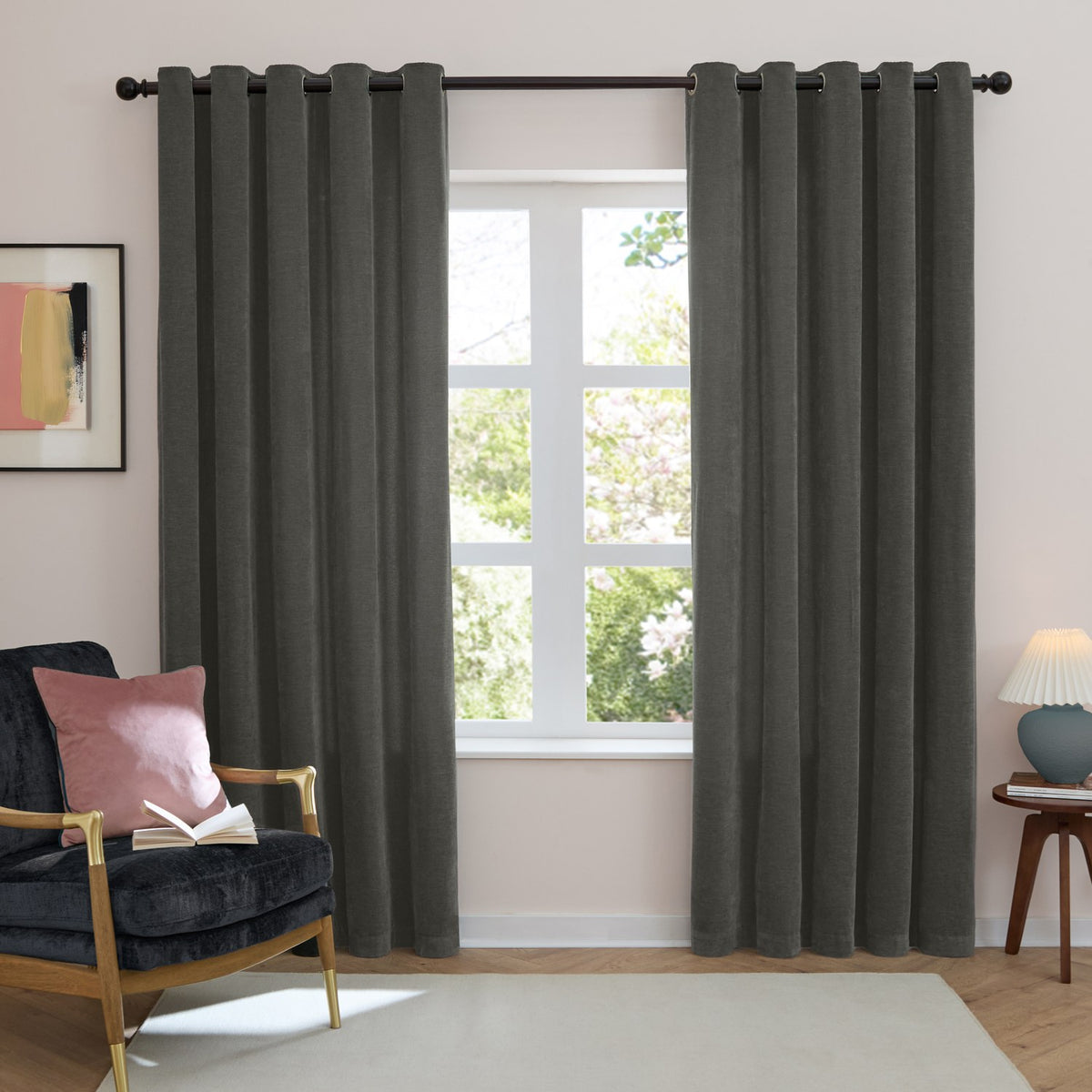 Charcoal grey chenille eyelet curtains with grommet top hung on a dark rod, shown floor-length either side of a window in a living room setting.