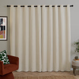 Ecru chenille eyelet curtains with dark grommets on a black rod, shown as a pair in a living room with a rust armchair and gallery-framed art.