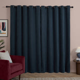Navy chenille eyelet curtains in a pair hang from a black rod with matte grommets, shown in a living room beside a red velvet armchair and pink wall.