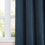 Navy chenille eyelet curtain panel in soft matte fabric, shown in deep folds beside a white-framed window overlooking greenery.