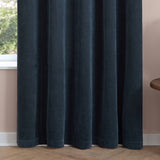 Navy chenille eyelet curtains with soft pleated folds and a hemmed base, shown against a pink wall beside a window in a living room setting.