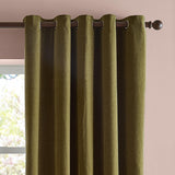 Olive green chenille eyelet curtains with matt textured fabric, fully lined panels hanging from a dark metal rod against a pink wall.