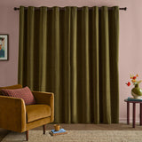 Olive green chenille eyelet curtains with a fully lined, matt finish hanging from a dark rod in a living room with pink walls, styled beside a mustard velvet armchair.