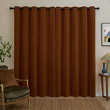 Rust chenille eyelet curtains with black grommet rings hung on a black pole in a living room with an armchair and side table.