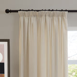 Ecru chenille pencil pleat curtain with gathered heading hung on a dark metal rod, shown in a living room beside a window and framed wall art.