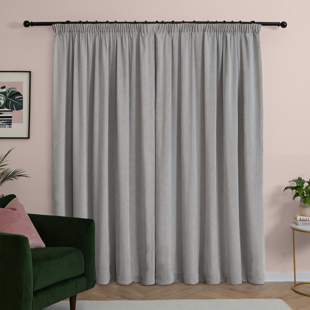 Silver-grey pencil pleat curtains in soft chenille fabric with a matt finish, shown fully drawn on a black rod in a living room with pink walls.