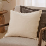 Slub Cotton Plain Linen Cushion in cream, square with flanged edges, shown on a beige armchair with a dark brown patterned cushion behind it.