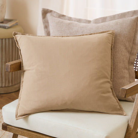 Slub Cotton Woven Plain Cushion in Natural beige with oxford border, shown on a chair against larger textured cushions in a living room setting.