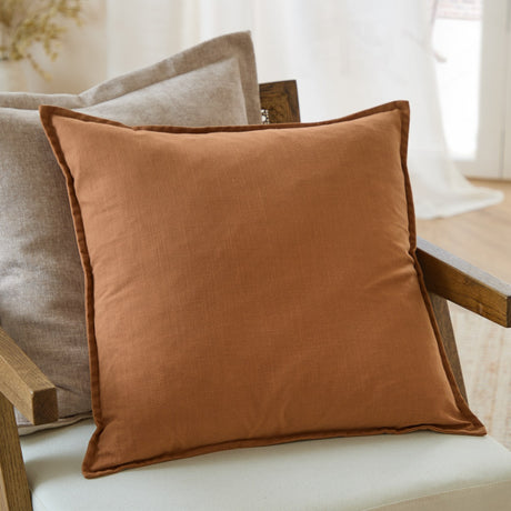 Slub Cotton Woven Plain Cushion in Toffee with an oxford flange border, styled on a neutral armchair beside a linen cushion in a living room setting.