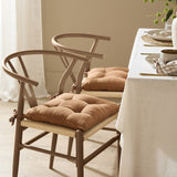 Toffee brown slub cotton seat pads with tie fastenings on wishbone-style dining chairs, styled at a table set for a meal.