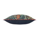Side view of the Seaweed Floral Velvet Cushion in indigo, a bolster-shaped cushion with coral-red flowers, green leaves and red piping on a navy velvet base, shown on a white background.