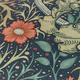 Close-up of the Seaweed Floral Velvet Cushion in indigo, showing coral-red flowers, green leaves and stems printed on dotted deep blue velvet fabric.