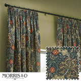 Pencil pleat curtains in indigo velvet with a Seaweed floral pattern in green, sand and coral, shown pleated on a black rod in a living room with olive green walls, plus a fabric swatch detail.