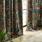 Seaweed Fully Lined Velvet Pencil Pleat Curtains in indigo, pencil pleat heading, shown in soft folds by a window with a William Morris floral and foliage print in coral, sand and green.