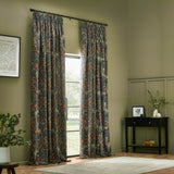 Seaweed fully lined velvet pencil pleat curtains in indigo with a Morris & Co. floral vine print, shown hanging in a green-toned living room beside a window.