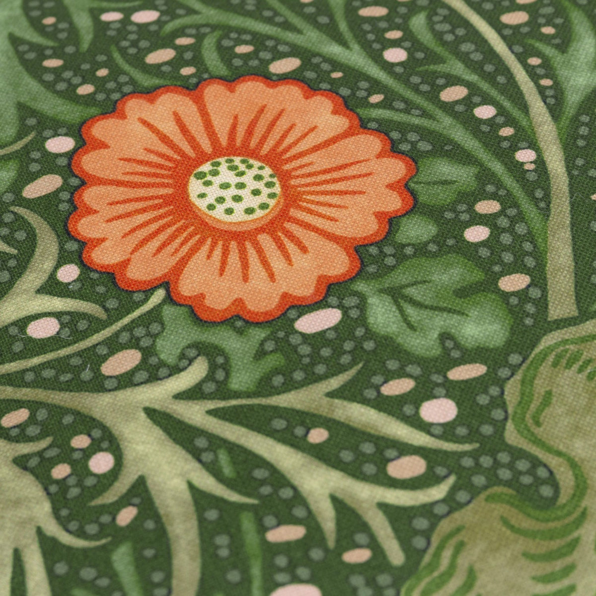 Close-up of the Seaweed Floral Polyester Cushion in Forest Green, showing a coral-orange daisy bloom with green centre on a scrolling sage and gold foliage pattern.