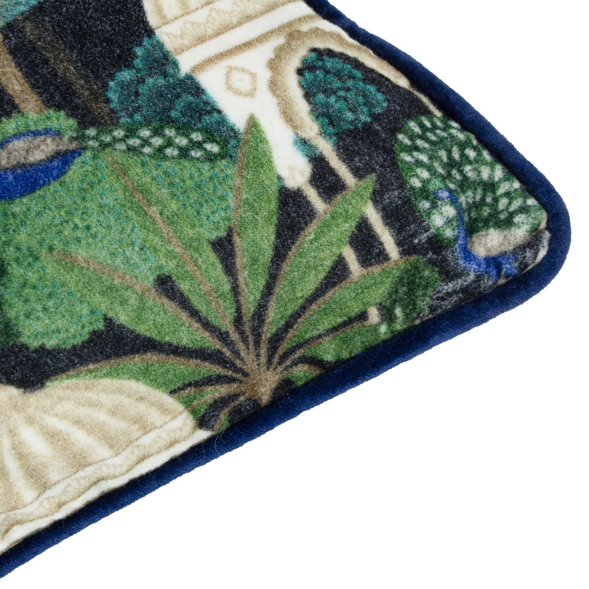 Corner detail of the Serenity Velvet Cotton Cushion in Midnight, showing a printed peacock and palm leaf design in green and blue with navy piped edging.