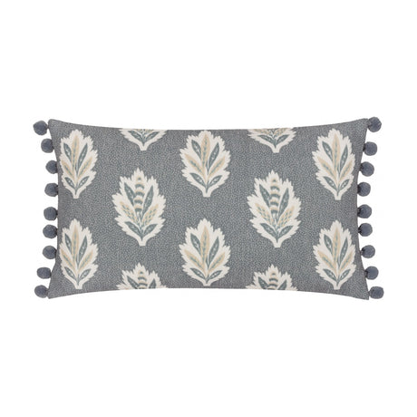 Sessile Leaf Reversible Cotton Cushion in Delph Blue, rectangular with cream, teal and gold leaf print on a blue-grey ground, edged with blue pom-pom trim, on a white background.