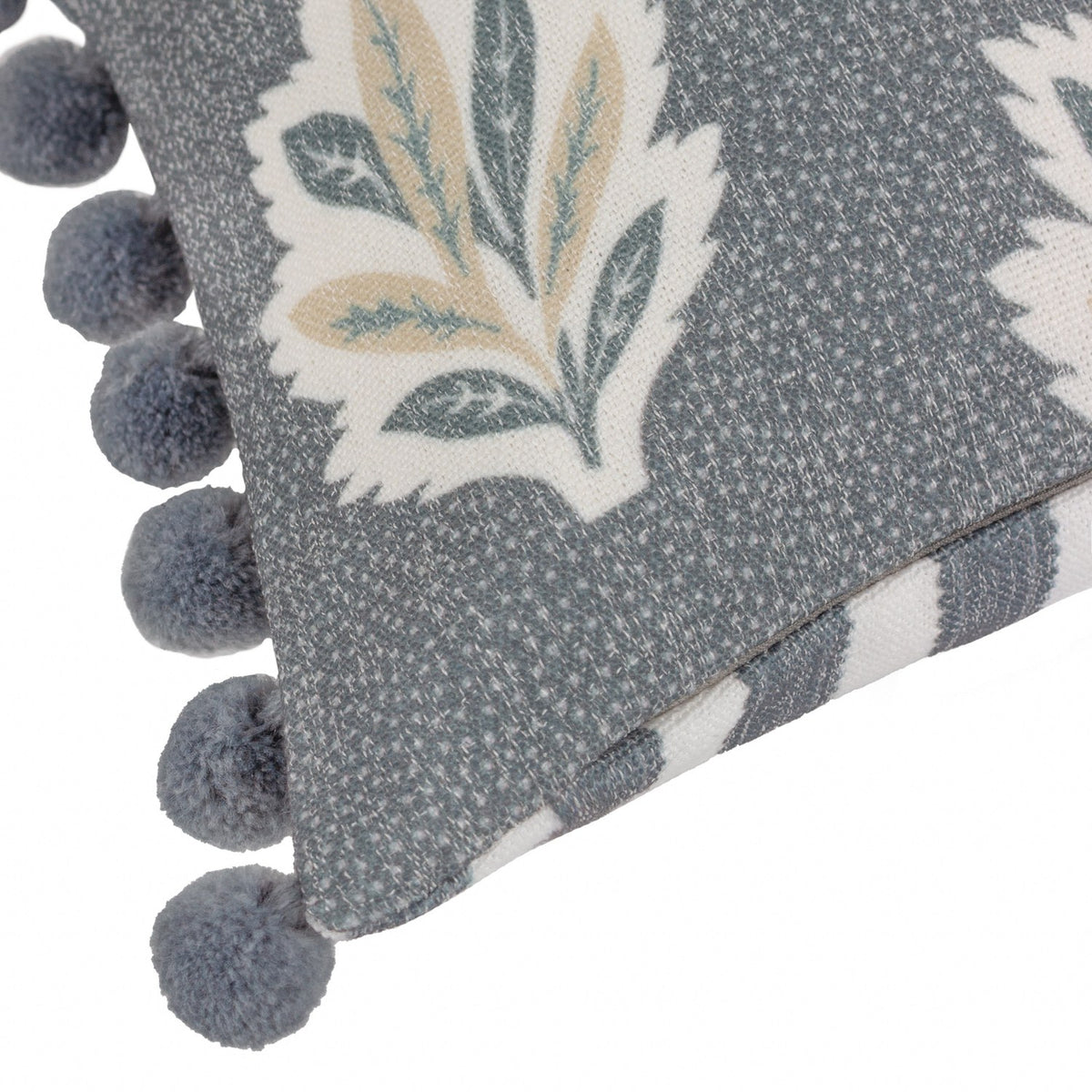Sessile Leaf Reversible Cotton Cushion in Delph Blue, corner detail showing printed leaf motif, reverse candy stripe, and chunky blue pom-pom trim on white background.