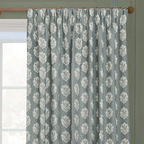 Sessile Leaf pencil pleat curtains in Delph Blue polyester, showing a repeating oak leaf motif in cream on a wooden pole above a window.