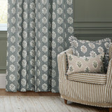 Sessile Leaf pencil pleat curtains in Delph Blue with a stacked oak leaf motif, shown as pencil-pleat drapes beside a striped armchair with matching leaf-print cushions.