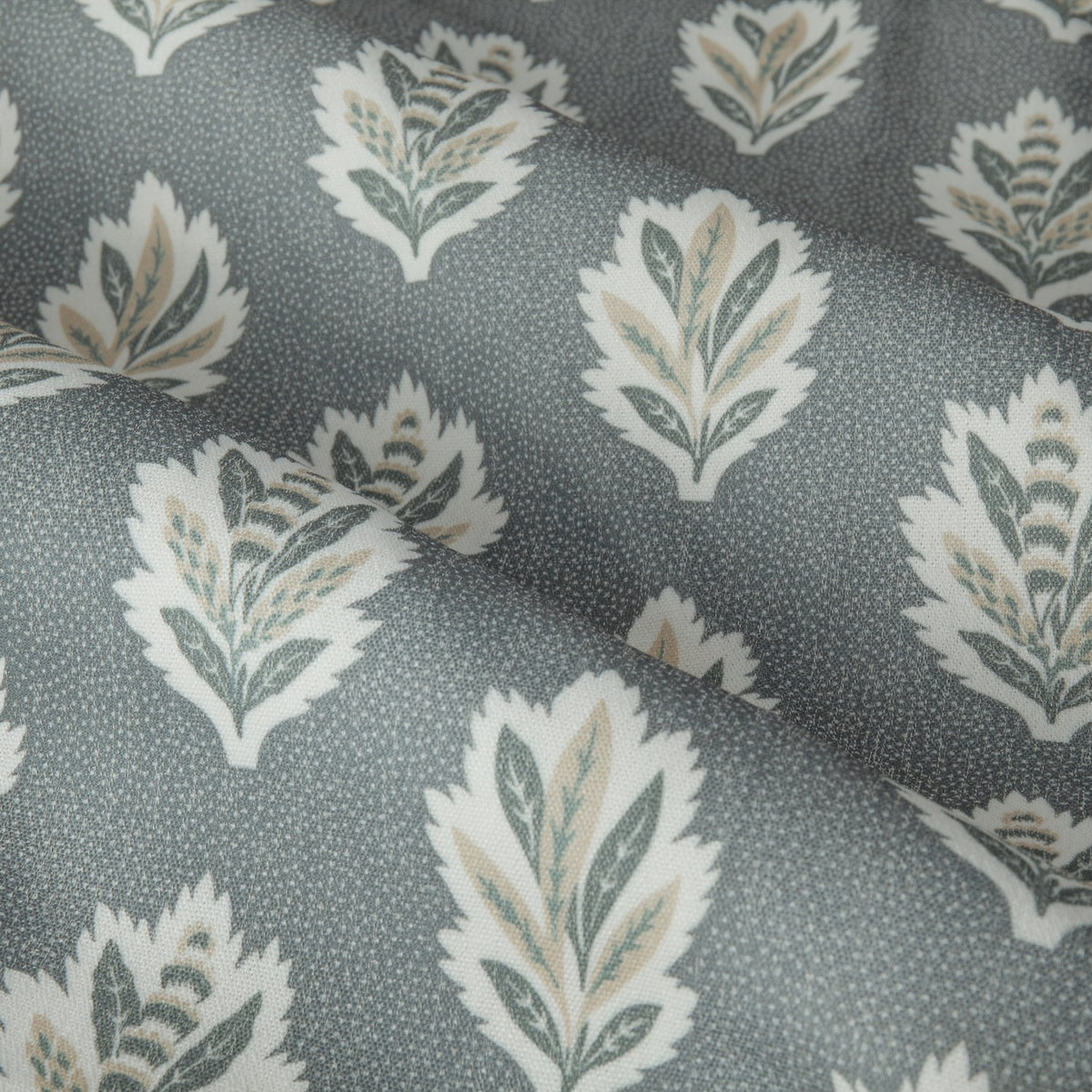 Close-up of Sessile Leaf pencil pleat curtain fabric in Delph blue, showing stylised oak leaf motifs in white, sage and tan on a spotted polyester ground.