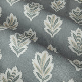 Close-up of Sessile Leaf pencil pleat curtain fabric in Delph blue, showing stylised oak leaf motifs in white, sage and tan on a spotted polyester ground.