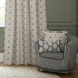 Sessile Leaf pencil pleat curtains in flax-beige polyester with green and slate blue leaf motif, shown pooling by a window beside a striped armchair with matching leaf-print cushions.