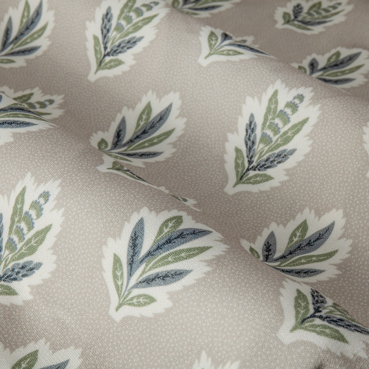 Sessile Leaf Floral pencil pleat curtain fabric in flax-beige, showing a repeat pattern of stylised oak-leaf motifs in green and slate blue on a spotted ground.